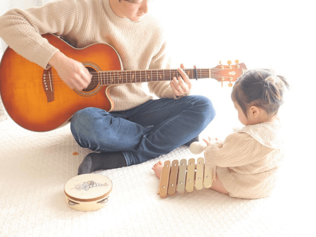 ギターを弾くパパと楽器を触る1歳娘
